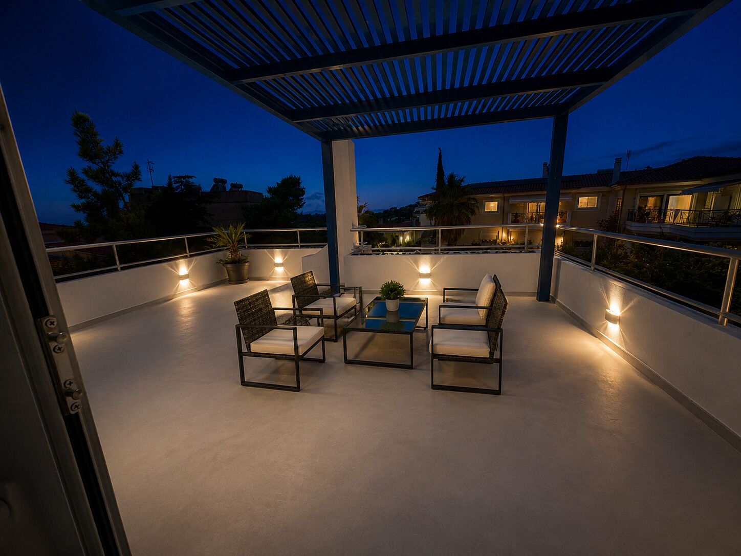 En udendørs patio med pergola, siddeområde og plantekasser.