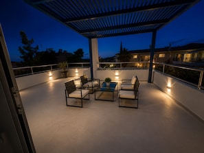 Une terrasse extérieure dotée d’une pergola, d’un espace salon et de plantes en pot.