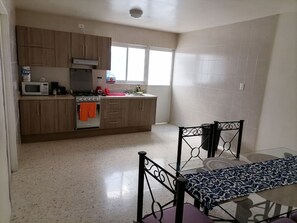 A kitchen with wooden cabinets, a microwave, an oven, and a window.
