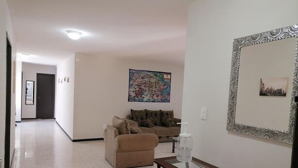 A living room with a sofa, a glass coffee table, and a framed picture on the wall.