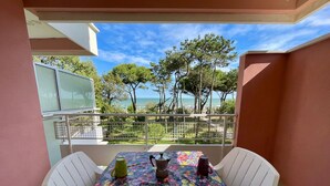 A balcony with a table set for two, a view of the sea, and a railing. - Apartment With Stunning sea View (Caorle)