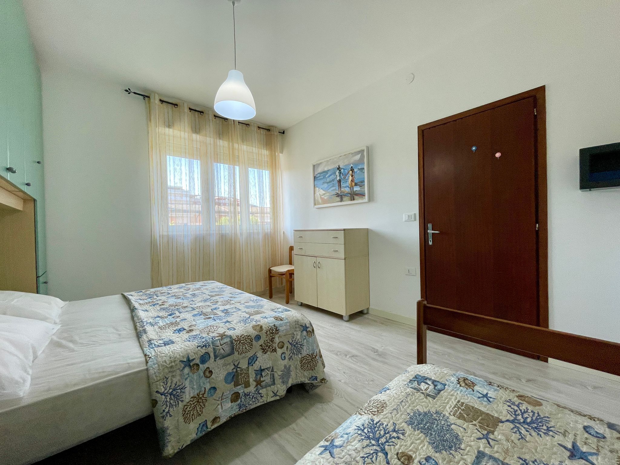 Un dormitorio con dos camas, un armario de madera, un escritorio y un cuadro en la pared.