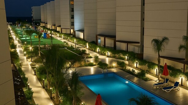 A nighttime view of a hotel pool area with a swimming pool, lounge chairs, and palm trees. - Sea Breeze Family Home (Al-Manasrah)