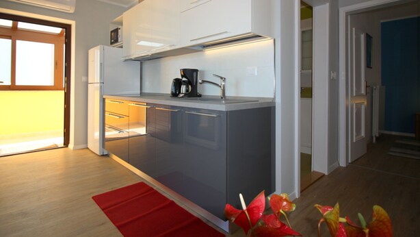Een moderne keuken met een centraal kookeiland, ingebouwde apparatuur en een rood kleed.