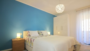 Een slaapkamer met een bed, nachtkastje, kledingkast en een hanglamp.