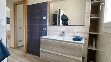 A modern bathroom with a large mirror, a sink, and a towel rack.
