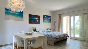 Ein modernes Schlafzimmer mit Bett, Esstisch mit Stühlen und Bildern an der Wand.