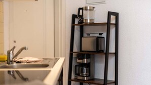 Et køkken med en indbygget hylde, hvor der står en kaffemaskine, en brødrister og en elkedel.