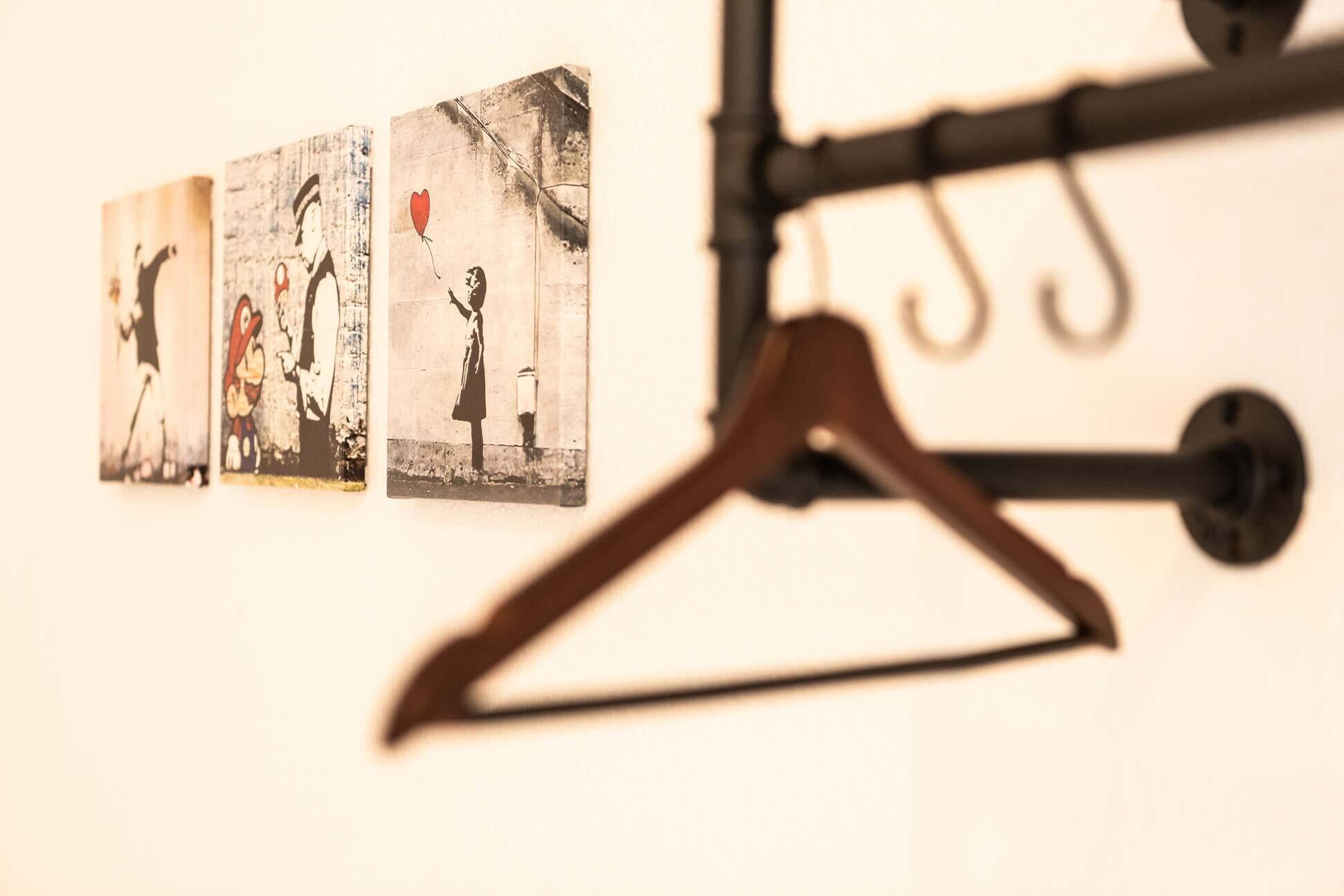 A wall with three framed pictures and a coat hanger.