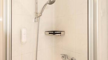 Ein Duschbereich mit Handbrause, Duschwand und Armaturen an der Wand.