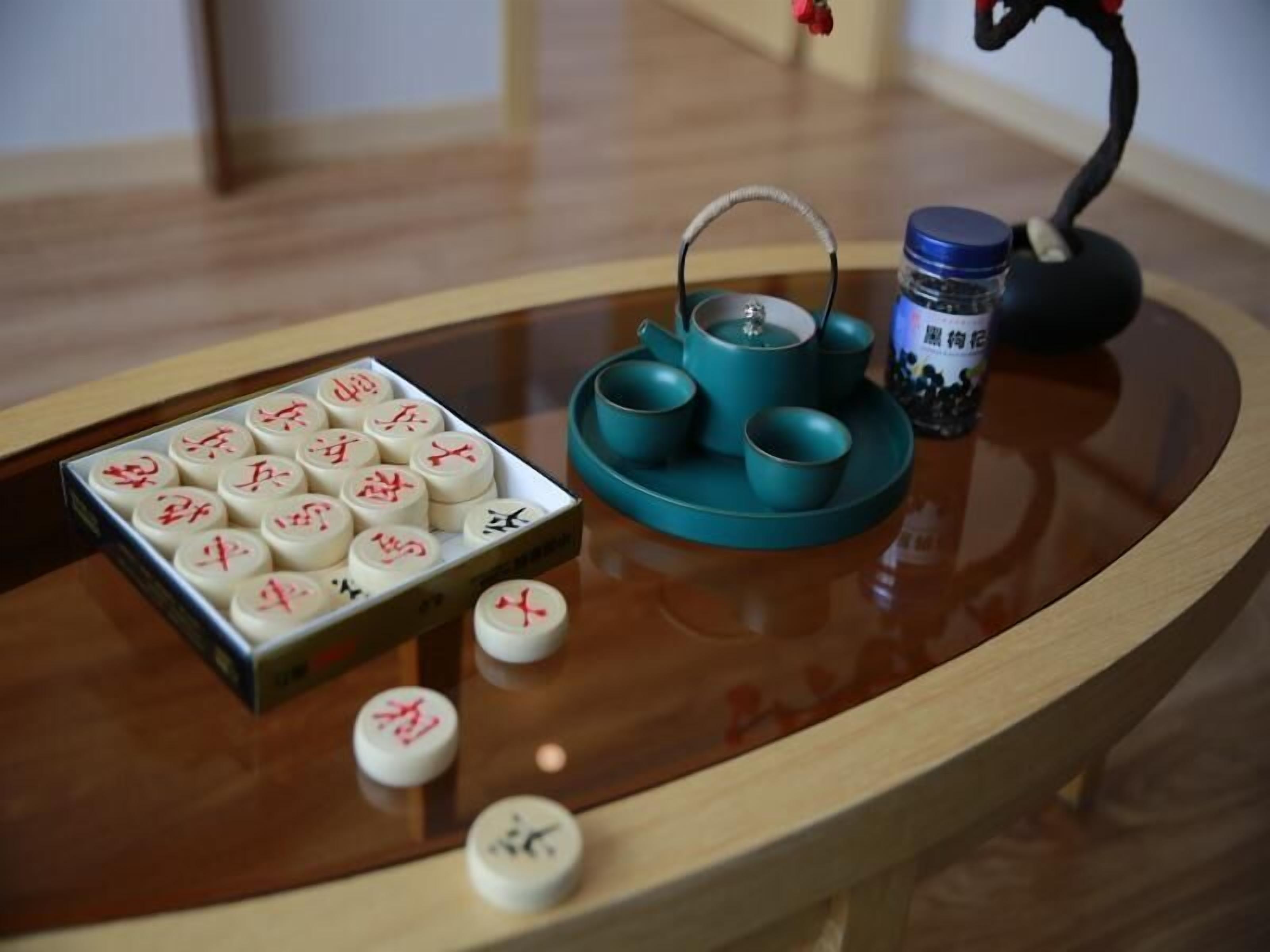 Una mesa con una tetera, tazas y una caja de fichas de Mahjong.