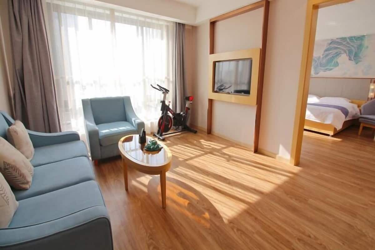 Ein Hotelzimmer mit Sofa, Couchtisch, Fahrrad, Bett und einem Gemälde an der Wand.