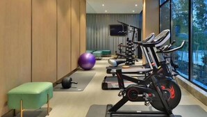 A modern gym with exercise equipment, a large window, and a green bench. - Greentree Eastern Suzhou Industrial Park Expo Center Qingjianhu Union Square Hotel (Suzhou)