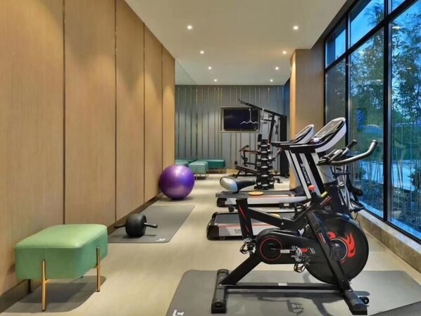 A modern gym with exercise equipment, a large window, and a green bench. - Greentree Eastern Suzhou Industrial Park Expo Center Qingjianhu Union Square Hotel (Suzhou)