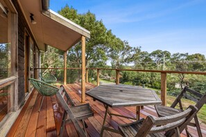 A wooden deck with a table and chairs, overlooking a natural landscape.