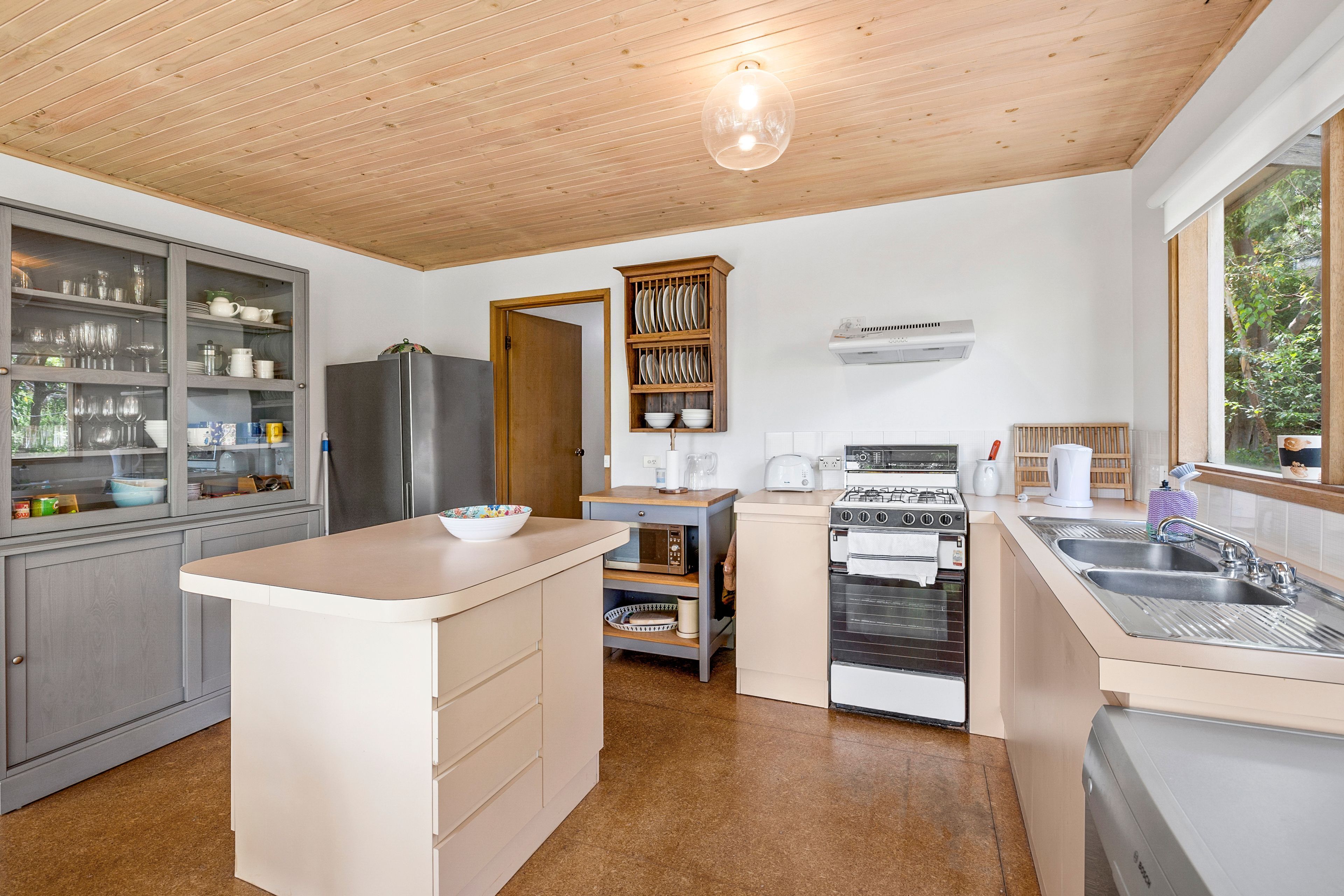 A modern kitchen with a central island, built-in appliances, and a window providing natural light.