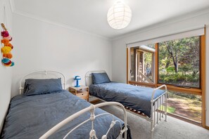 Ein Schlafzimmer mit zwei Betten, einem Fenster mit Blick auf Bäume und einer hängenden Deckenleuchte.