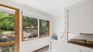 A room with a bunk bed, a radiator, and a view of a garden through a large window.