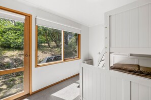 A room with a bunk bed, a radiator, and a view of a garden through a large window.
