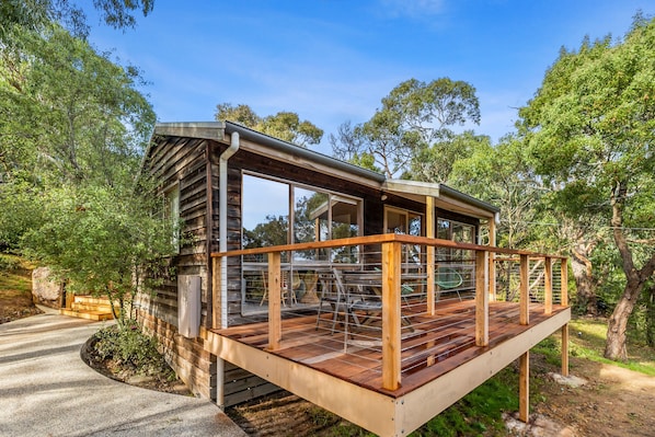 A wooden deck with a railing, surrounded by trees.