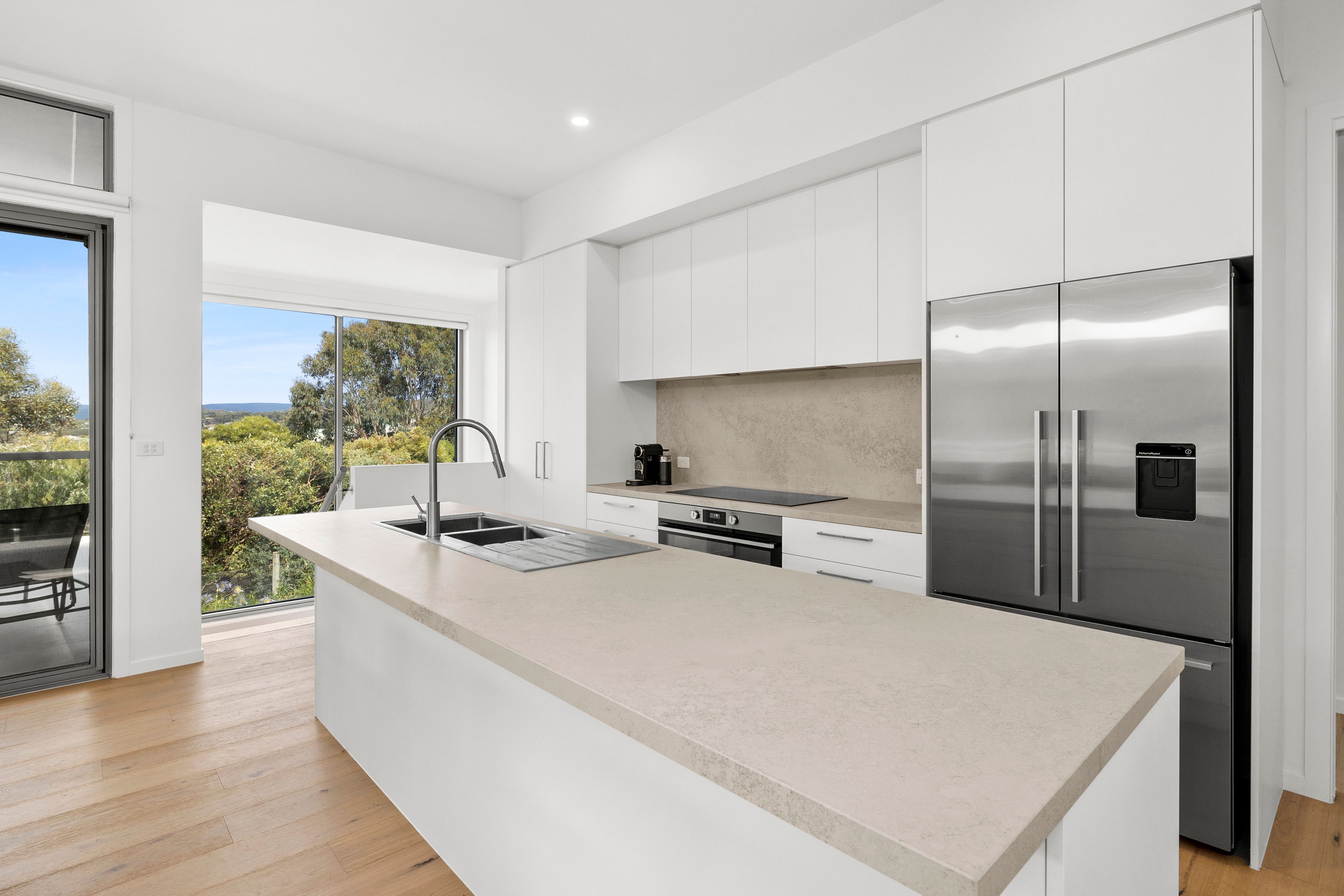 A modern kitchen with a large island, stainless steel appliances, and a view of the outdoors.