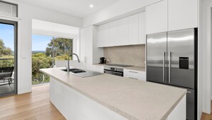 A modern kitchen with a large island, stainless steel appliances, and a view of the outdoors. - Aireys Sunset Beach House (Aireys Inlet)