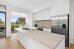 A modern kitchen with a large island, stainless steel appliances, and a view of the outdoors. - Aireys Sunset Beach House (Aireys Inlet)