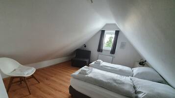 Une petite pièce propre, avec un lit simple, une chaise et une fenêtre.
