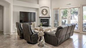 A living room with a flat-screen TV, leather recliners, a fireplace, and a large glass door leading outside. - Camelback Corridor, 5 min from Airport, Pool & Sun (Phoenix)