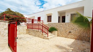 Un edificio bianco con un muro in pietra e un cancello rosso.