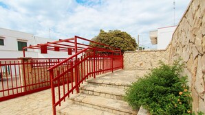 Una scala in pietra con ringhiere rosse che conduce all'ingresso di un edificio.