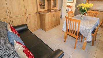 A cozy living room with a sofa, a dining table with chairs, and wooden cabinets.