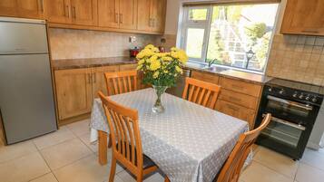 Una cocina con armarios de madera, un refrigerador, una estufa y una mesa de comedor con sillas.