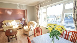 A living room with a sofa, armchairs, a dining table with chairs, and a view of the outside. - Lavender Cottage (Castletownbere)