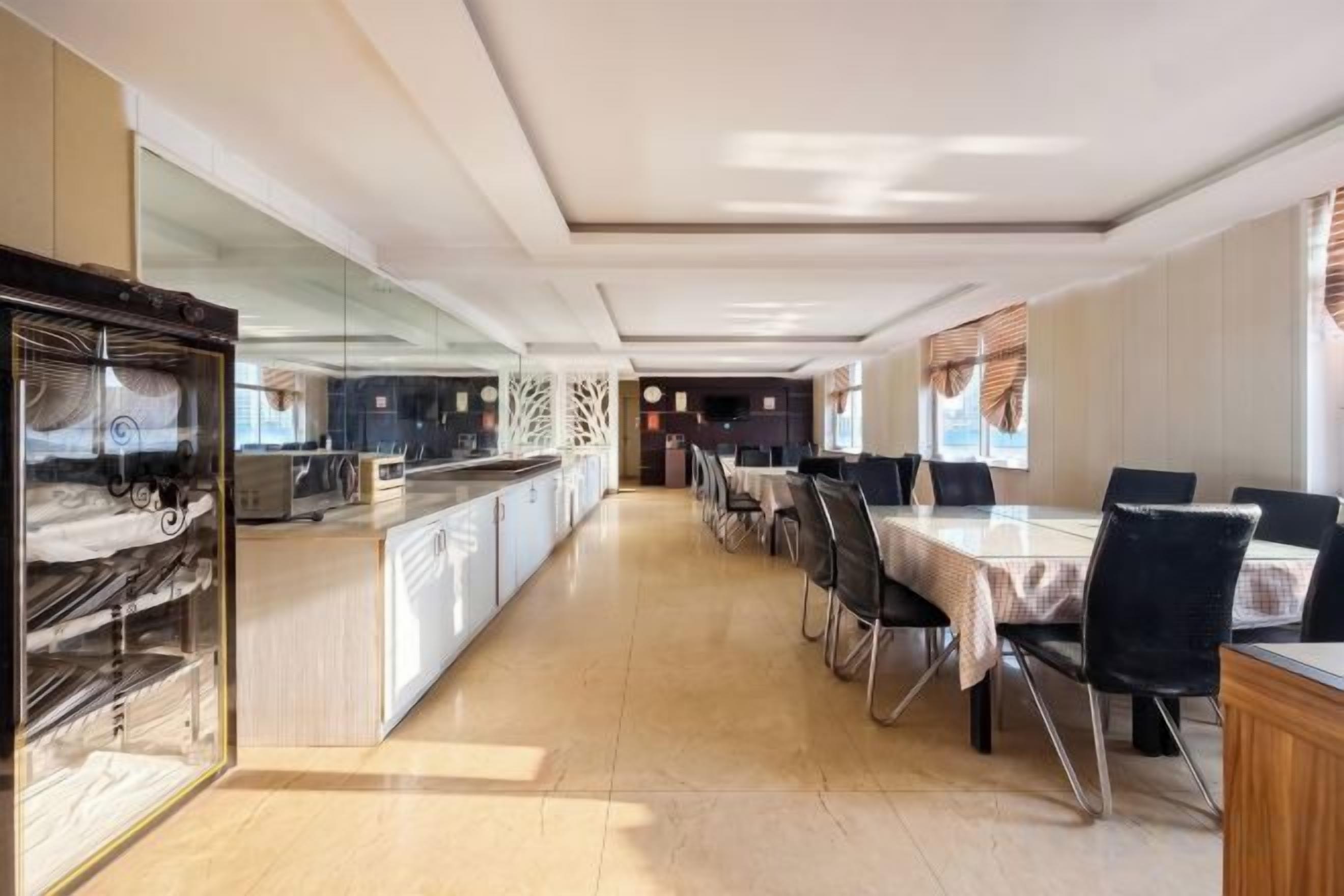 A hotel dining area with a long counter, multiple tables, and chairs.