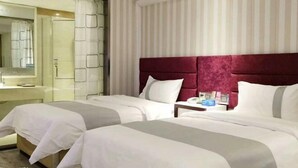 Quarto de hotel com duas camas, um espelho grande e parede listrada.