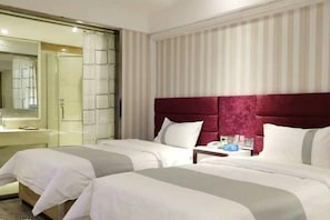 Habitación de hotel con dos camas, un espejo grande y una pared a rayas.