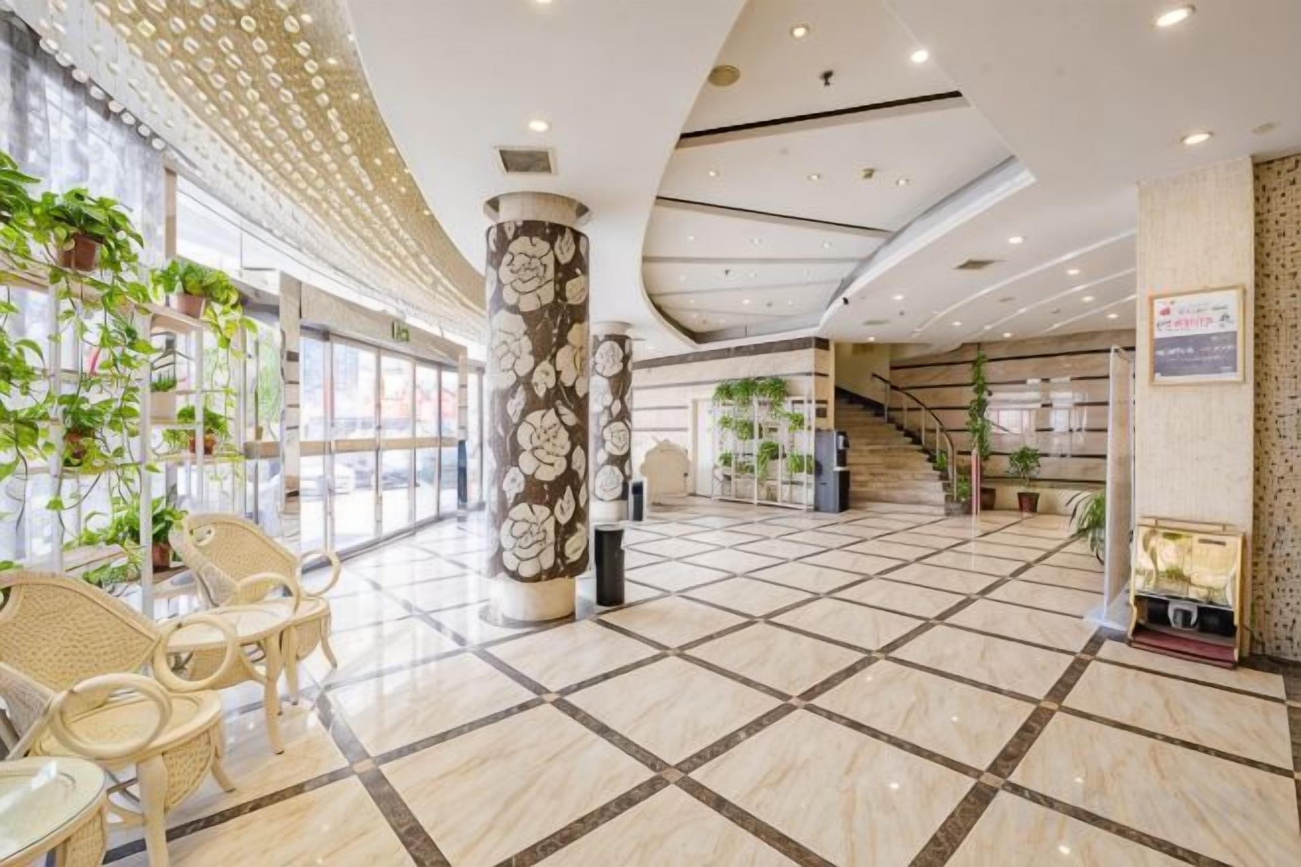 A spacious lobby with a tiled floor, seating area, and decorative columns.
