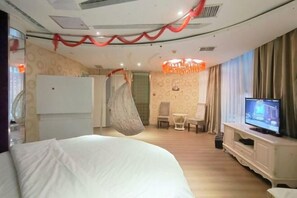 Una habitación de hotel con una cama, televisión, una mesita y una silla.