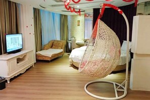 Une chambre d’hôtel équipée d’un fauteuil suspendu, d’un lit, d’une télévision et d’un bureau.