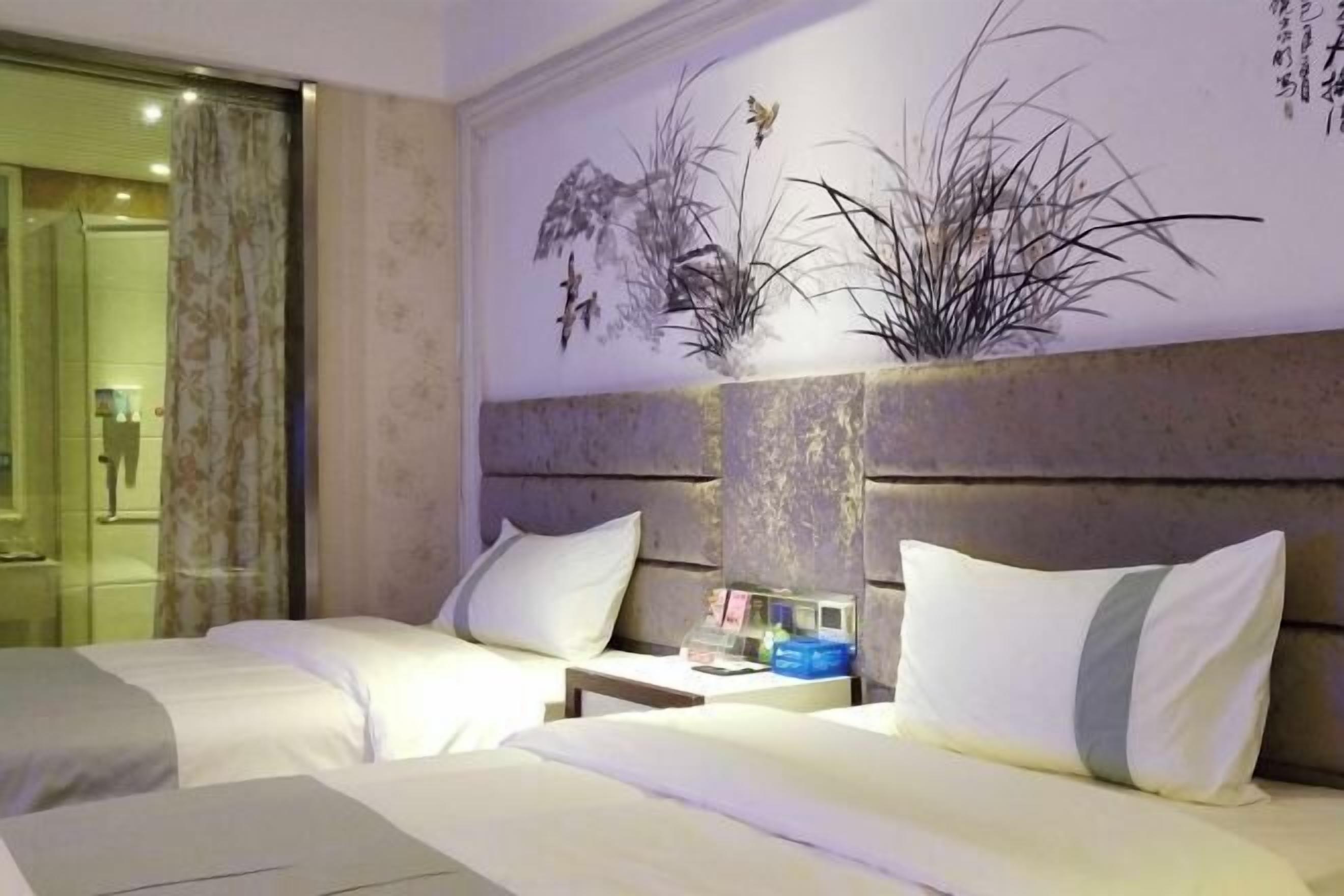 Habitación de hotel con dos camas, una mesita de noche y una obra de arte colgada en la pared.