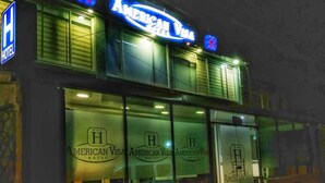 Un hotel con un cartel grande de Visa Americana y un logotipo azul en forma de 'H' en la fachada.