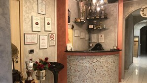 Zona de recepción con un muro de mosaico de azulejos, una mesa de recepción y diversas distinciones y certificados exhibidos en las paredes.