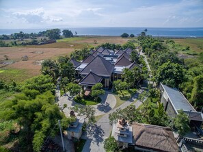 Vista aérea de um resort com vários edifícios, um gramado bem cuidado e vista para o oceano.