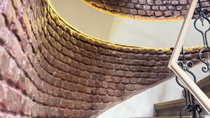 Una escalera en espiral con un muro de ladrillo y barandilla metálica.