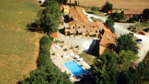 Vista aérea de una propiedad rural con piscina, rodeada de árboles y algunos edificios.