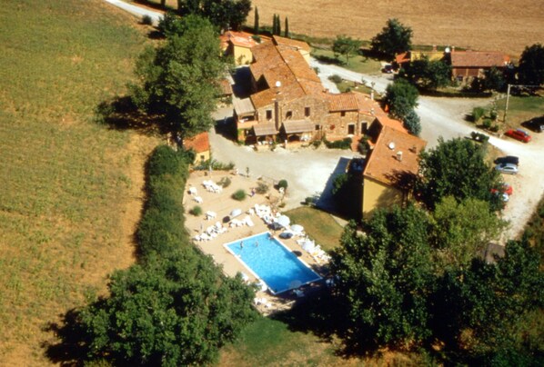 An aerial view of a rural property with a swimming pool, surrounded by trees and a few buildings. - Superior Ground Floor Apartment With Pool View (Casole d'Elsa)