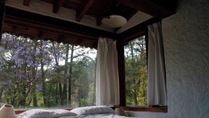 A bedroom with a bed, a window with curtains, and a view of trees. - Country House In The Woods With River (Valle de Bravo)