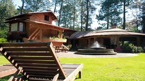 A rustic house with a patio, a wooden lounge chair, and a fountain. - Country House In The Woods With River (Valle de Bravo)