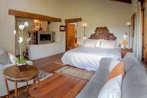 A bedroom with a bed, a sofa, a small table with a plant, and a television. - Country House In The Woods With River (Valle de Bravo)
